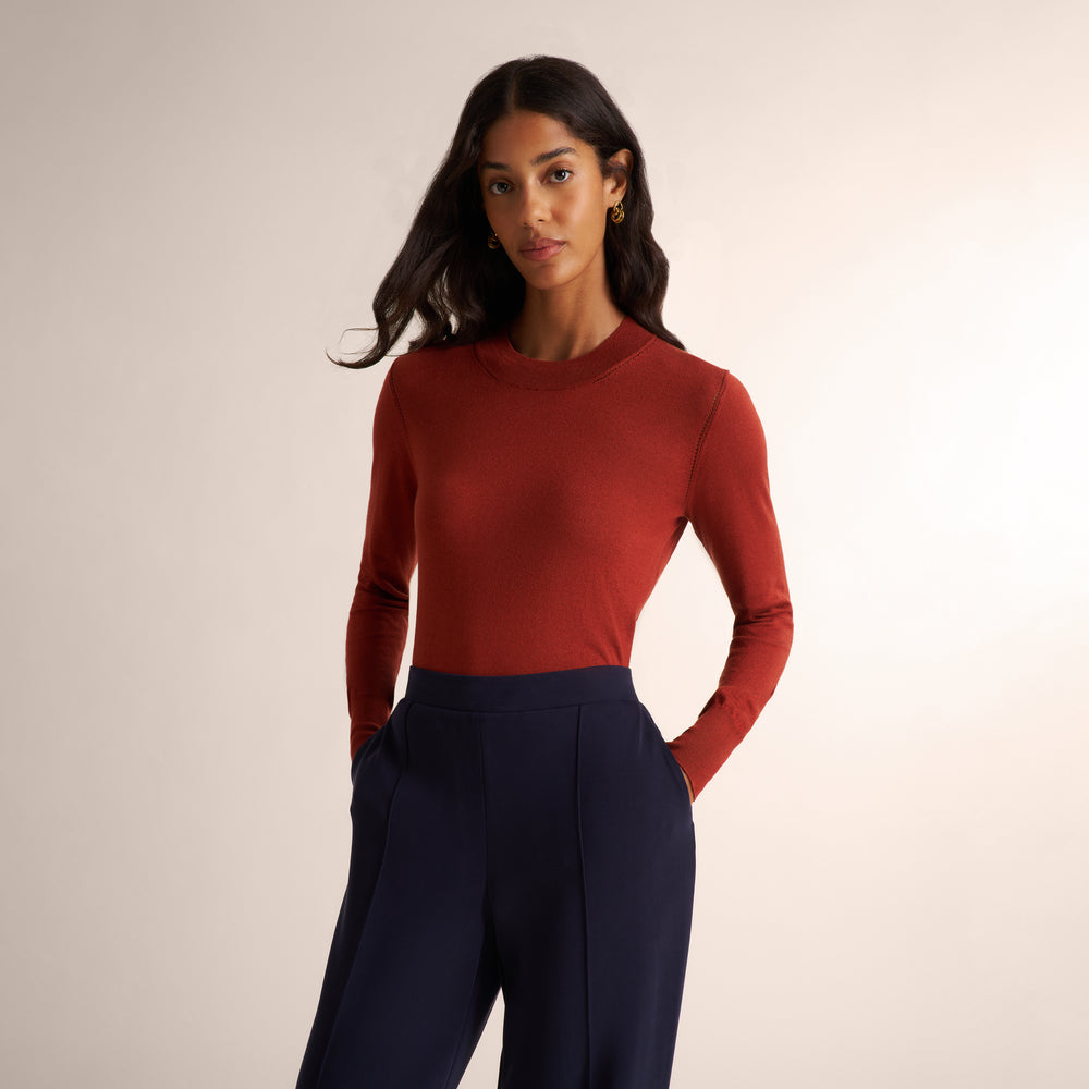 Woman wearing a orange spice color long sleeve sweater with a matching navy wide leg pants