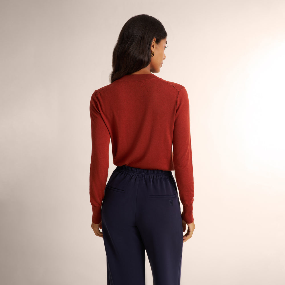 Woman wearing a orange spice color long sleeve sweater with a matching navy wide leg pants