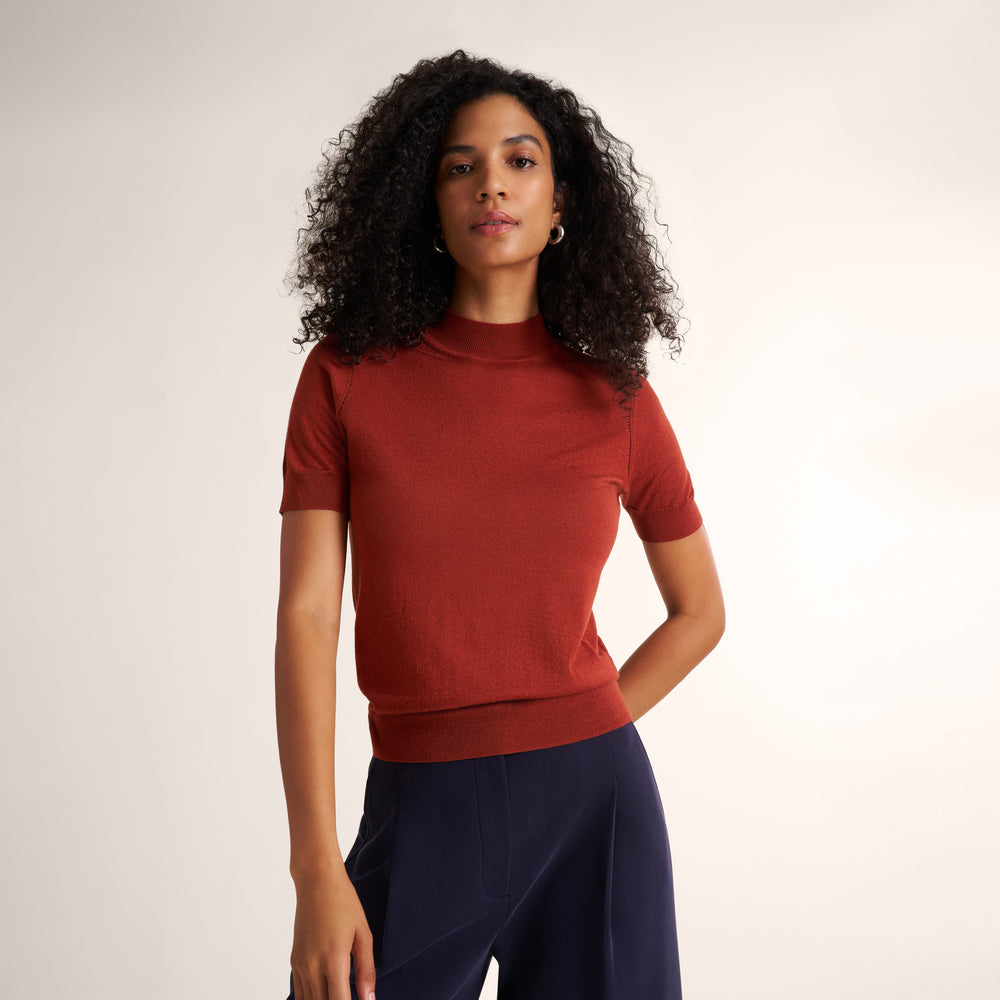 Woman wearing an orange spice color short sleeve sweater with navy wide leg pants