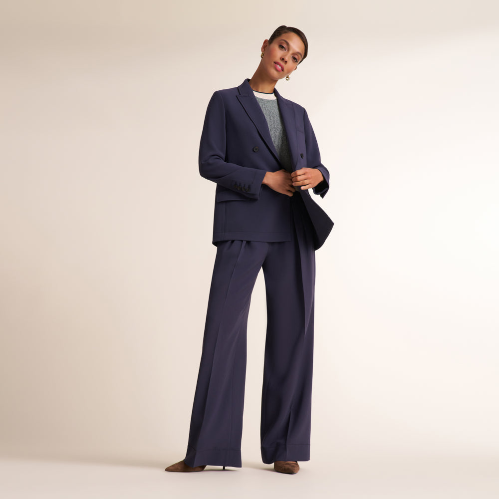 Woman wearing a navy and white knit tank top with navy pleated trouser pants