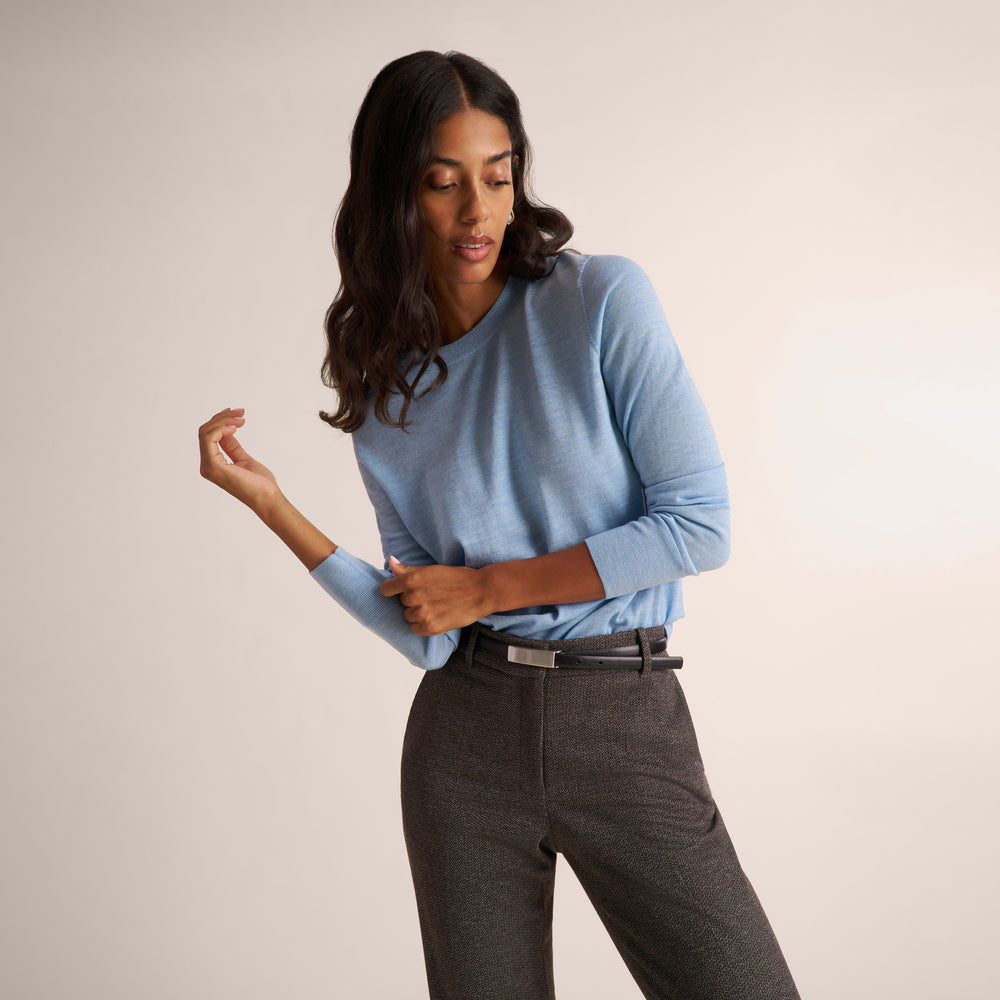 Woman wearing a light blue long sleeve sweater with dark gray herringbone pants