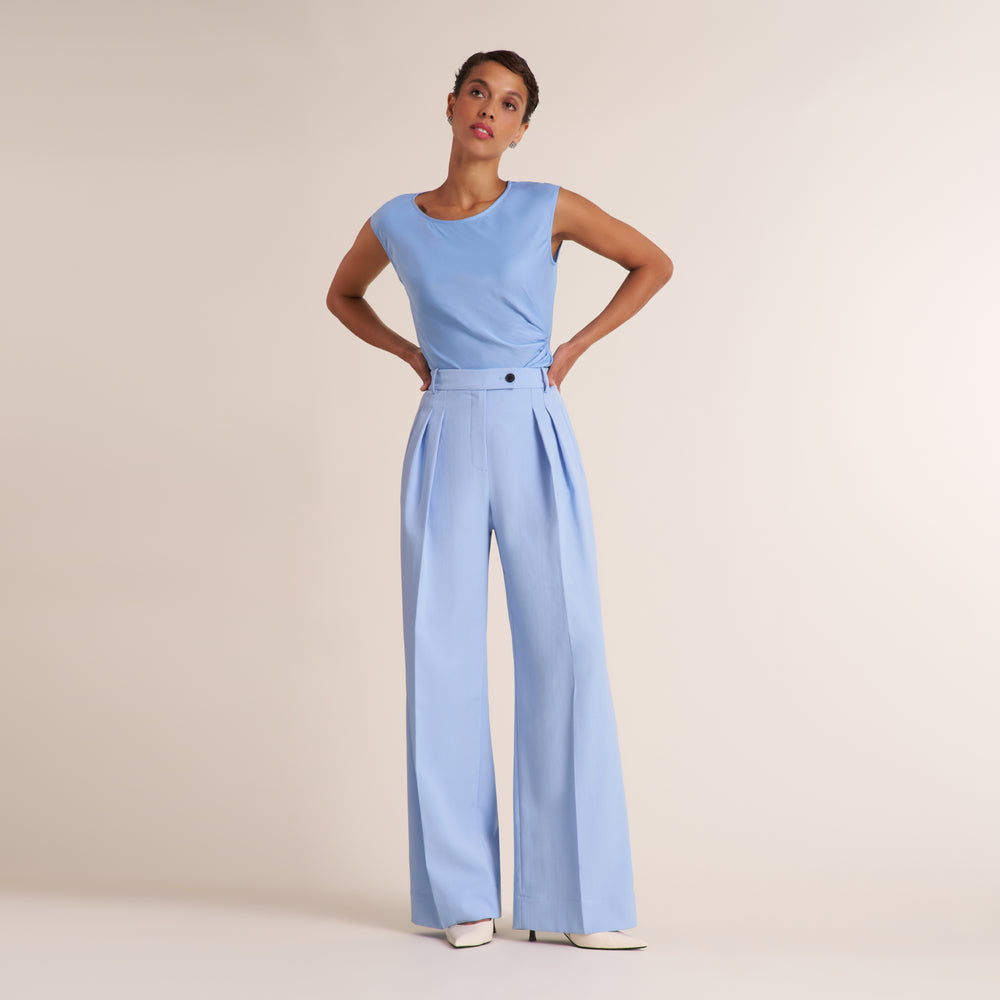 Woman wearing a light blue pant and top on a beige background