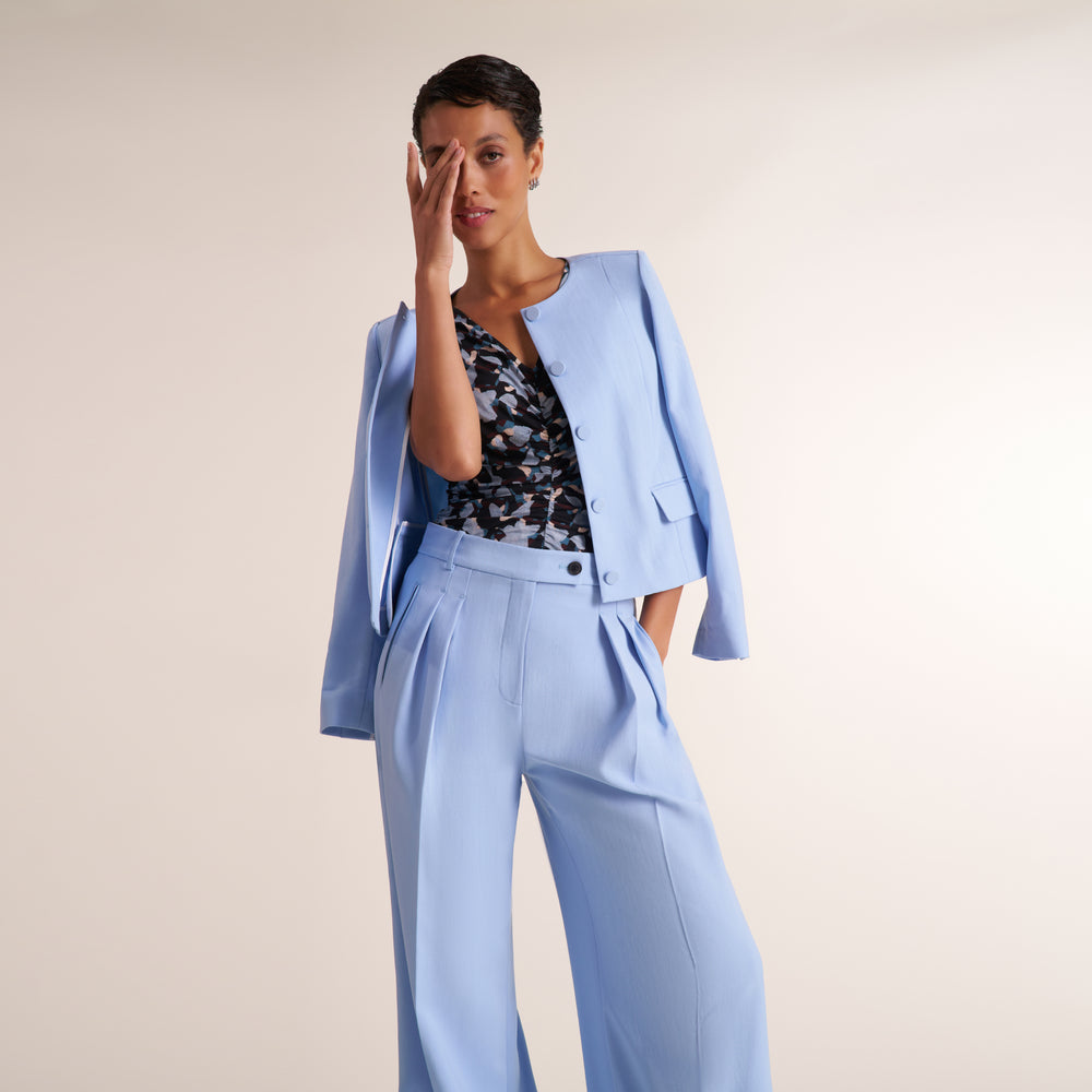 Woman wearing a light blue jacket and pant with a floral shirt