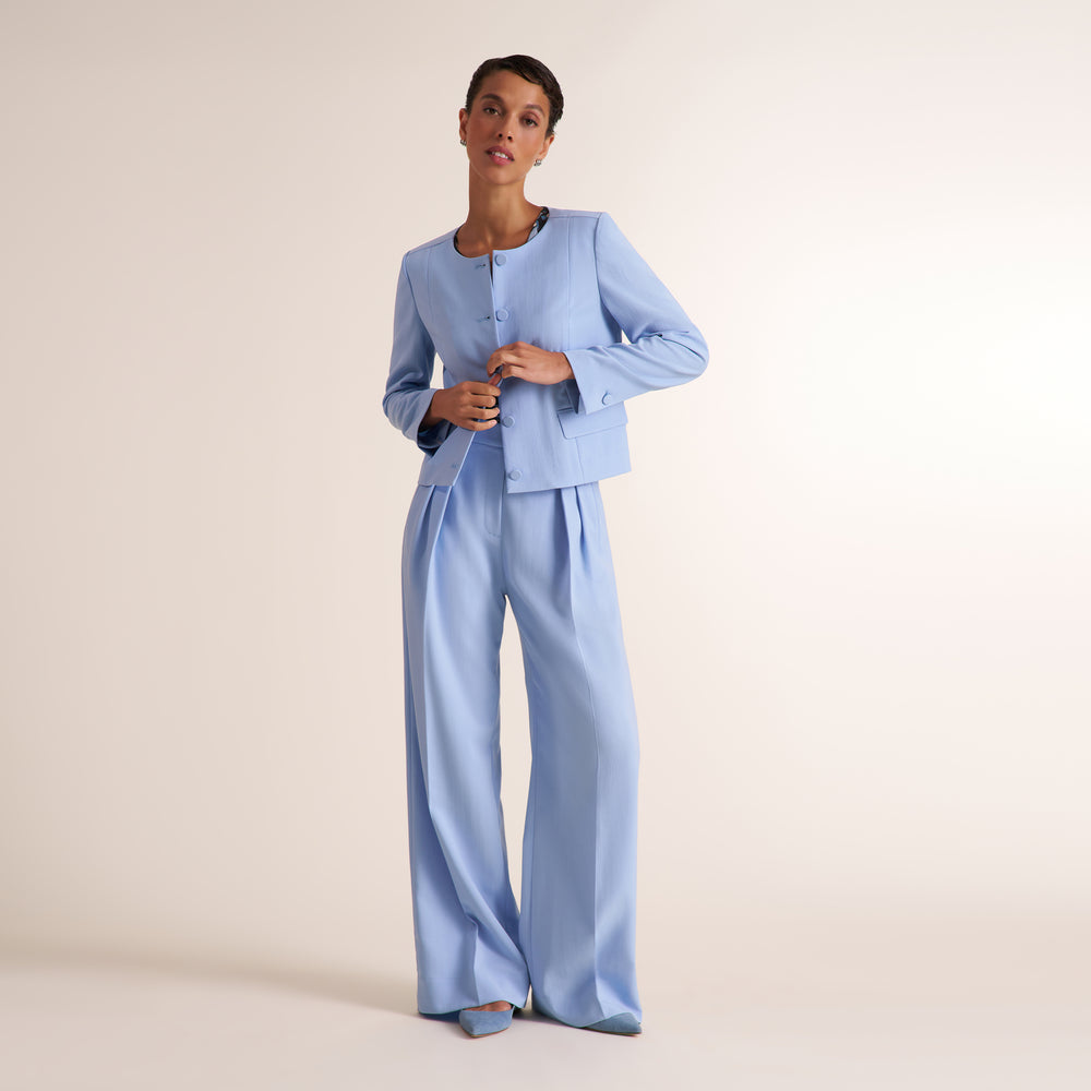 Woman wearing a light blue jacket and pant with a floral shirt