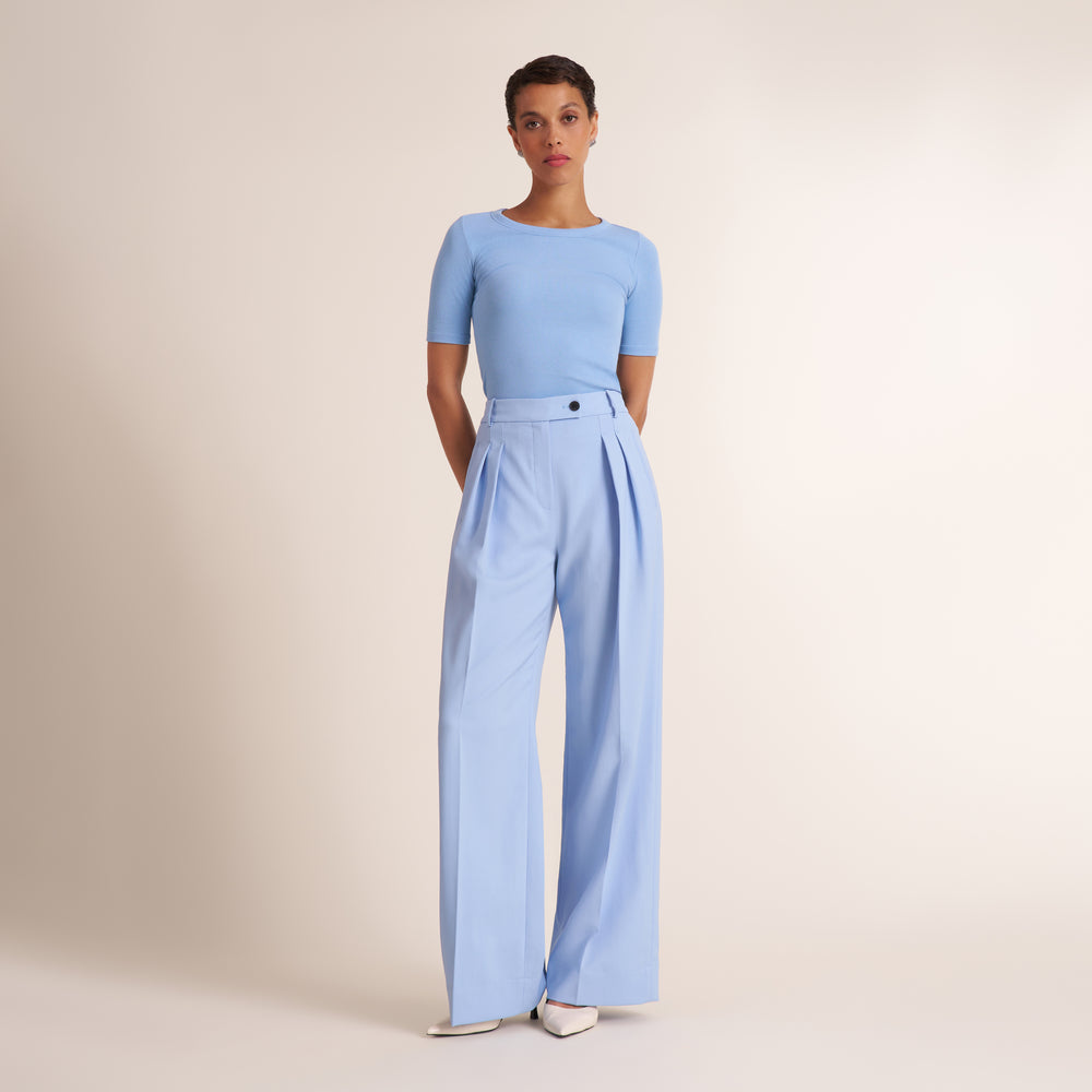 Woman wearing a light blue pant and top on a beige background