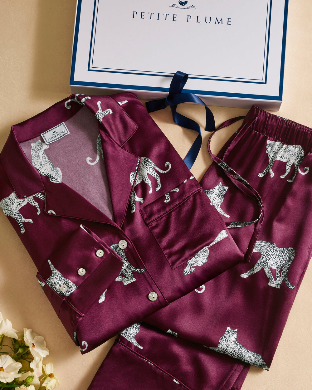 Maroon pajama set with animal pattern on a beige surface, featuring the brand 'Petite Plume'.