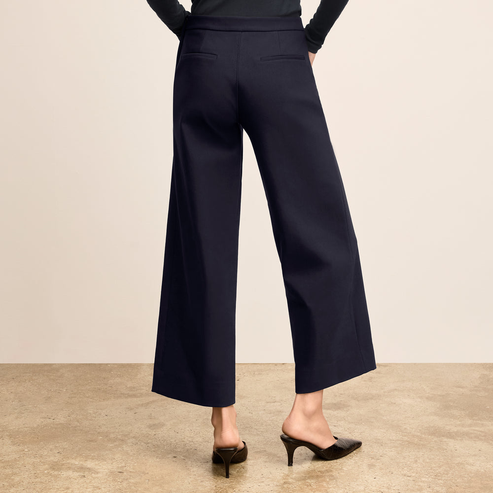Person wearing navy blue wide-leg pants on a plain background