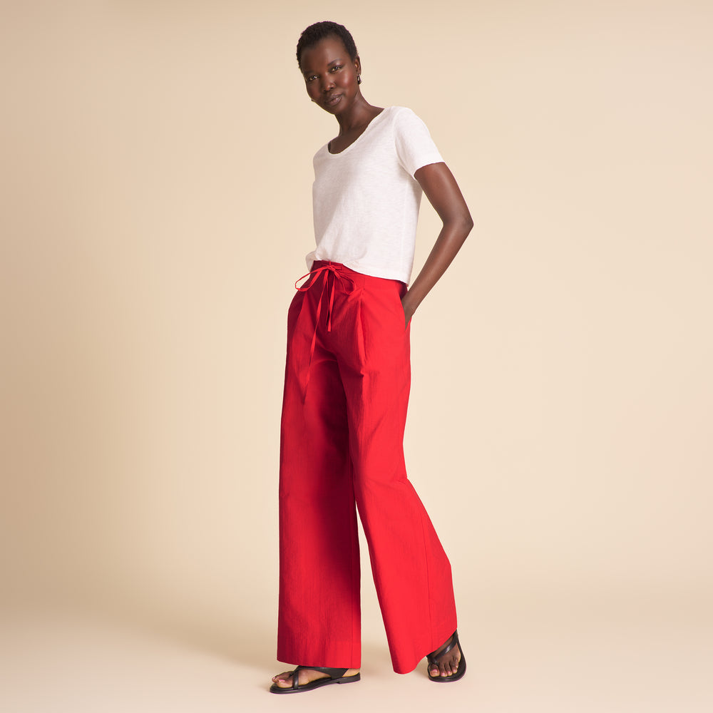 Woman wearing red pants on a beige background.