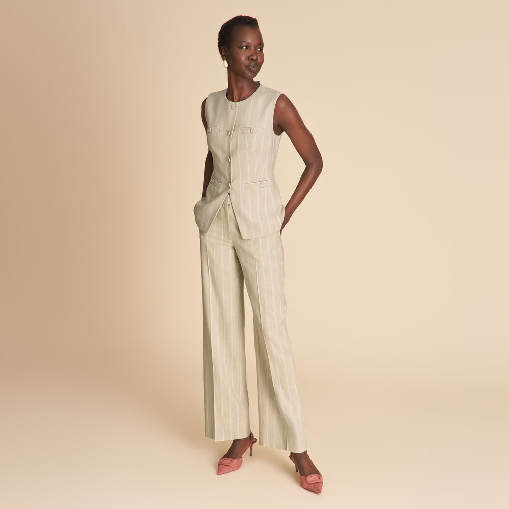 Woman wearing a light-colored jumpsuit on a beige background