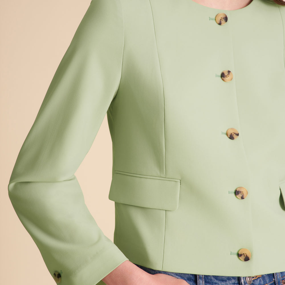 Green jacket with button details on a beige background