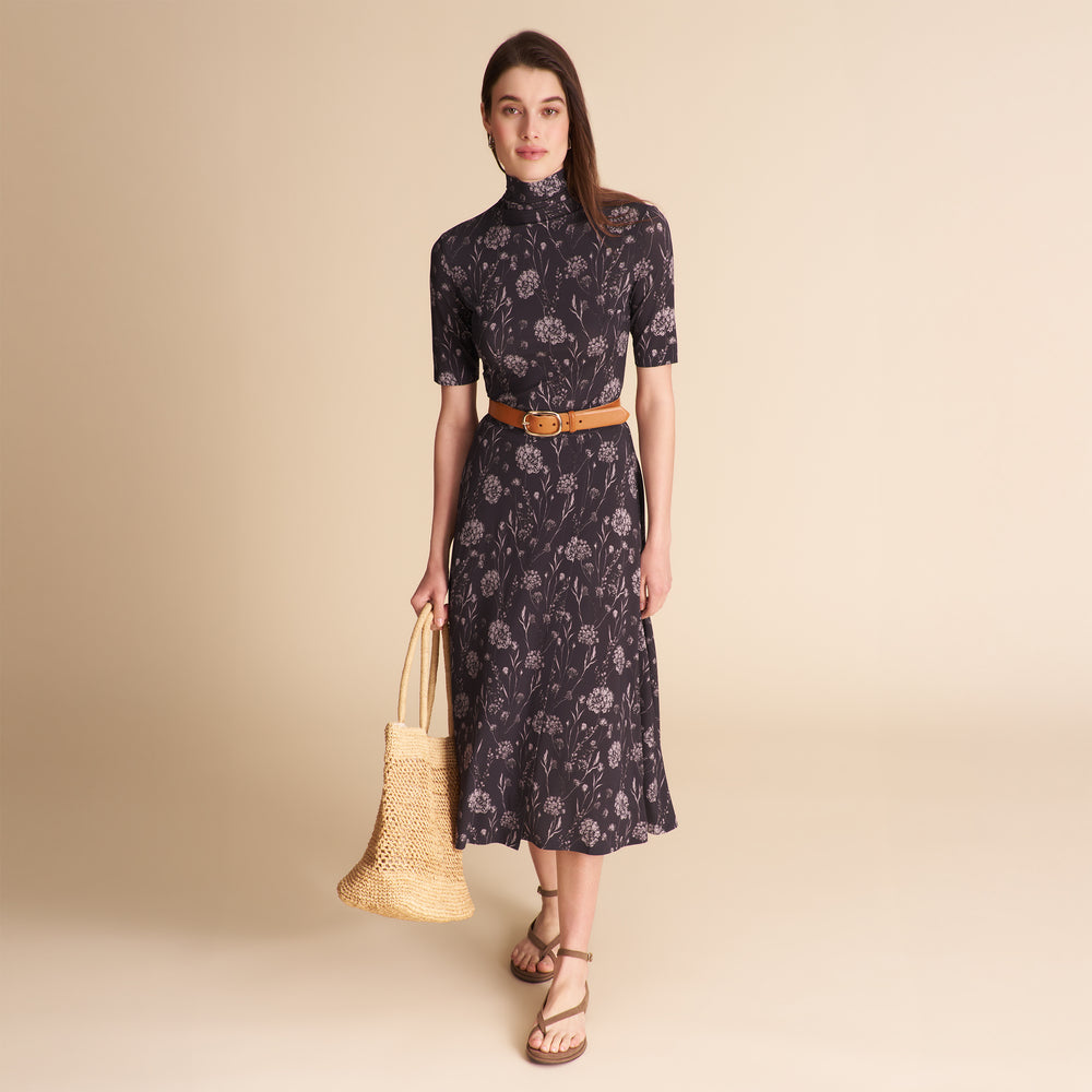 Woman wearing a dark floral matching top and skirt on a beige background
