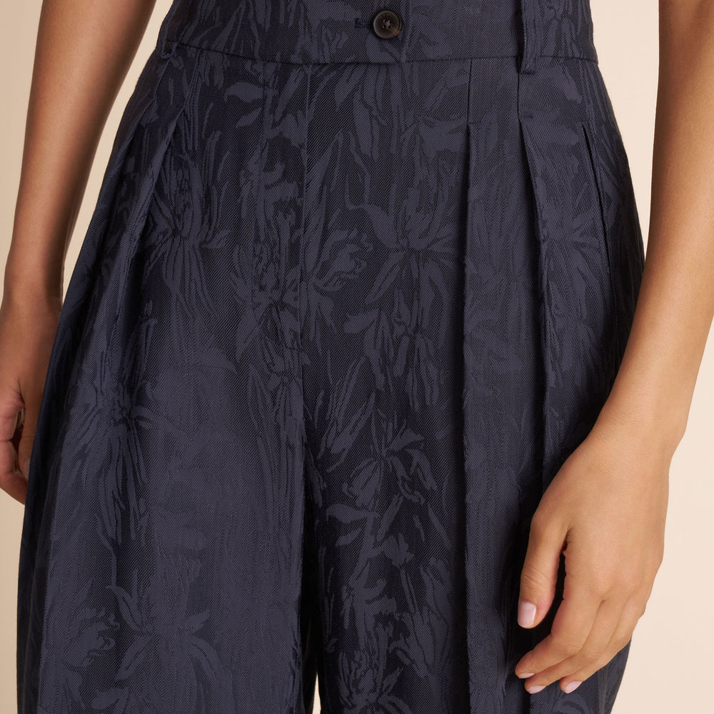 Navy blue pleated skirt with floral pattern on a beige background