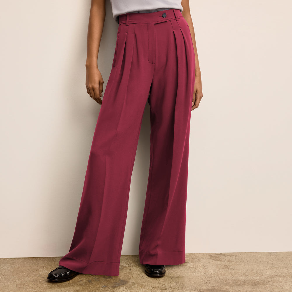Person wearing maroon wide-leg pants against a beige wall.