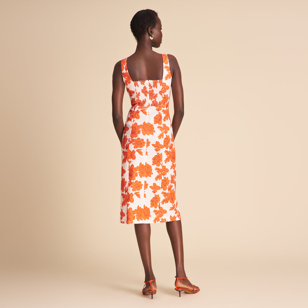 Woman in an orange and white floral dress standing on beige background