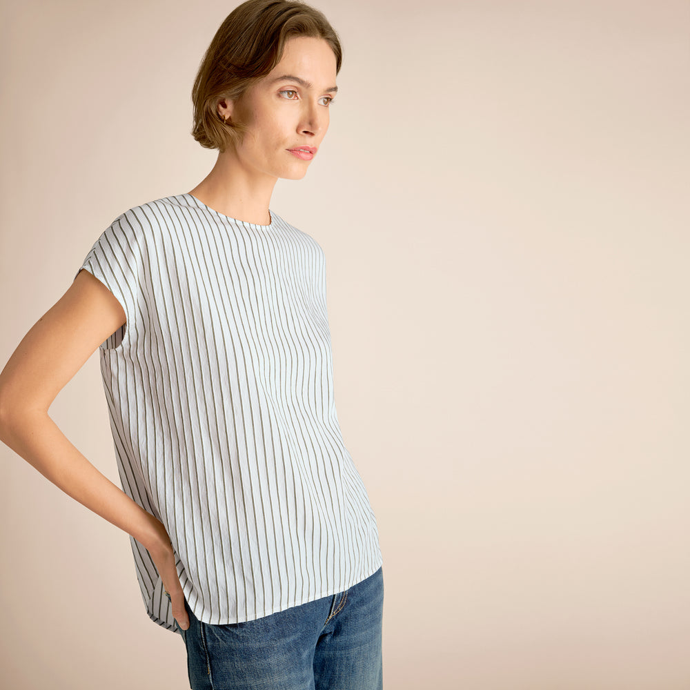 Woman wearing a striped shirt and jeans against a beige background