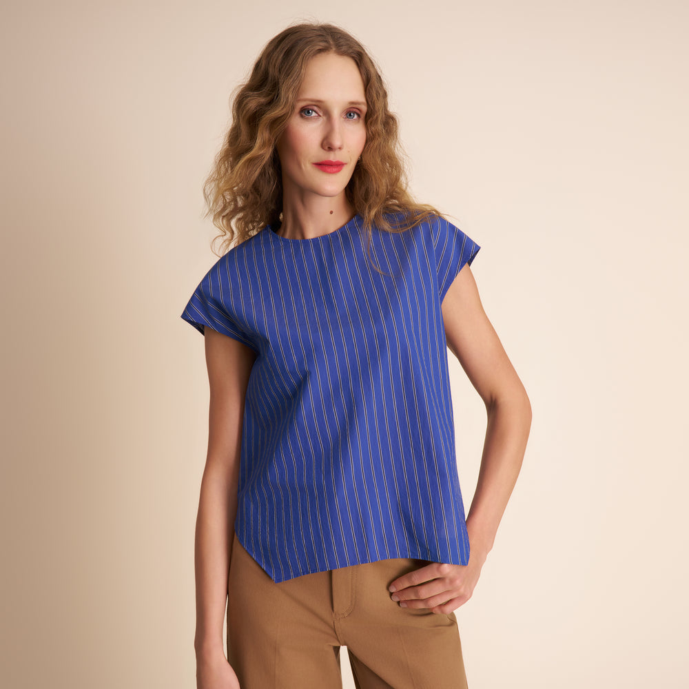 Woman wearing a blue striped shirt against a beige background