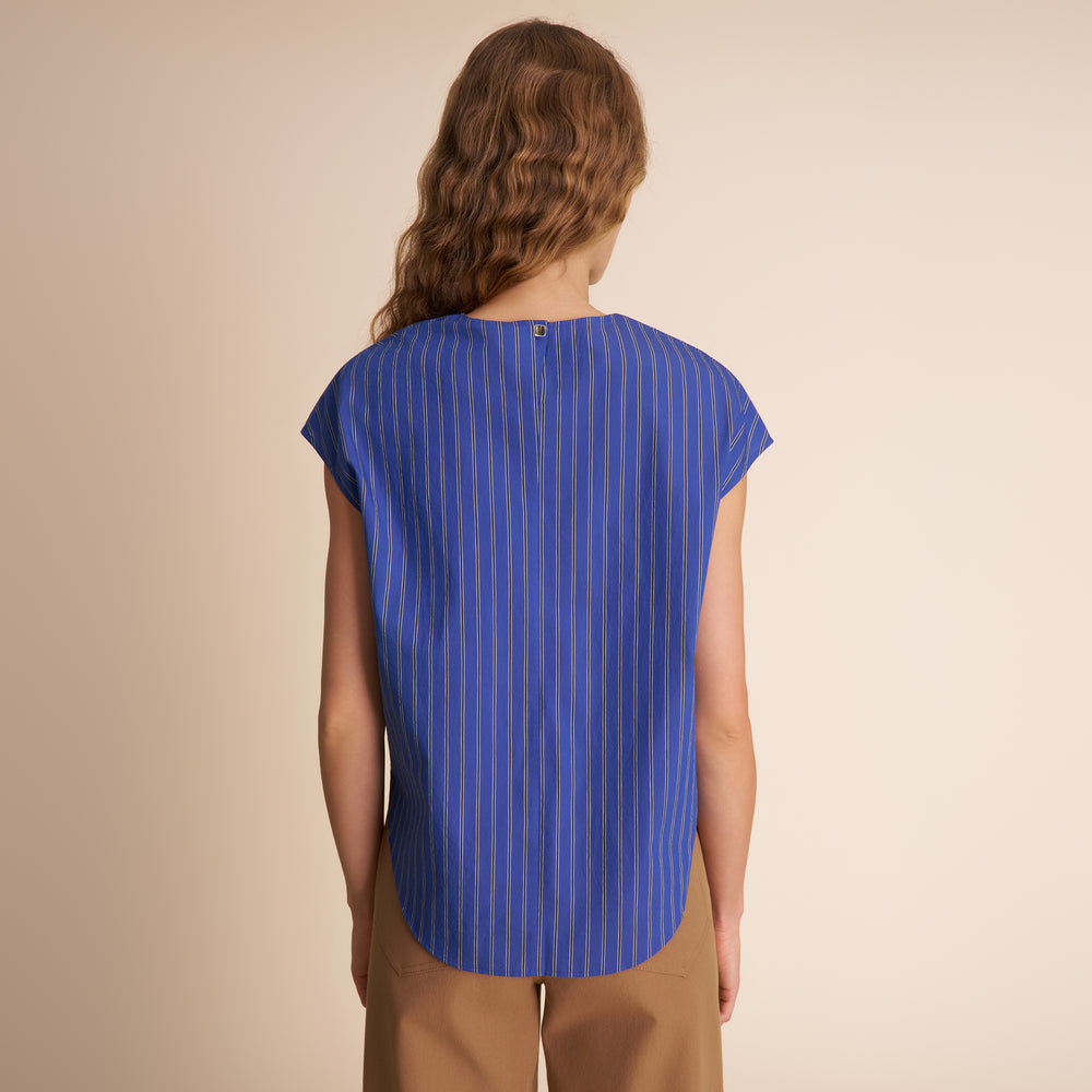 Woman wearing a blue striped shirt against a beige background
