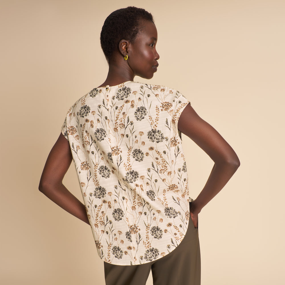 Woman wearing a floral blouse against a beige background