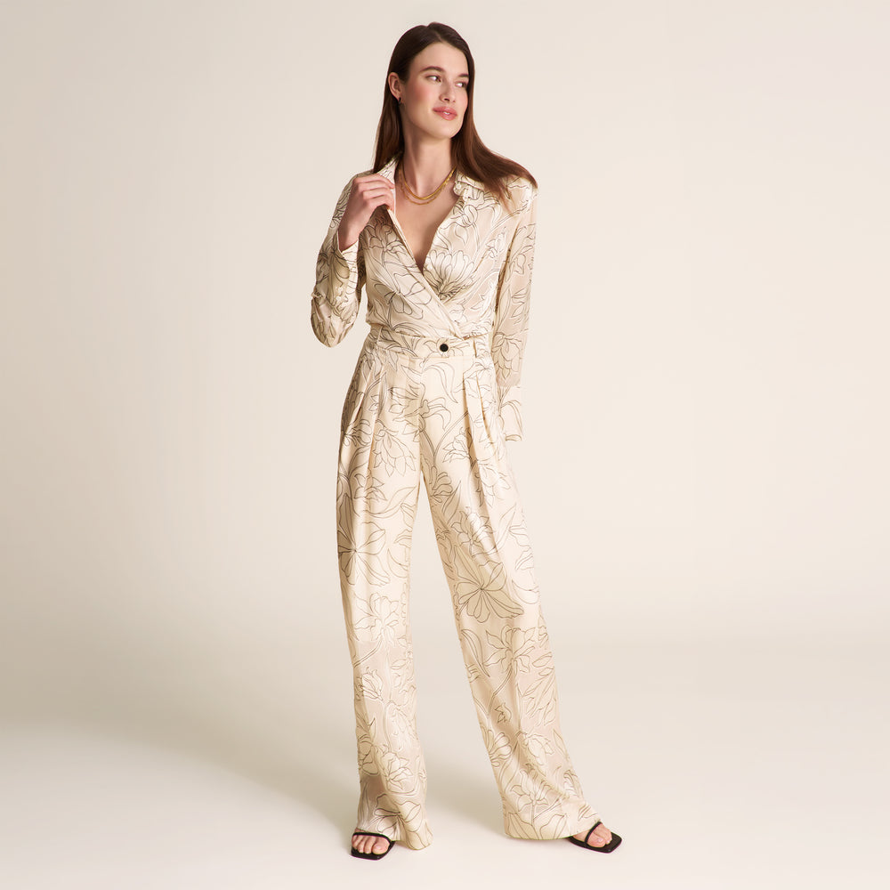 Woman wearing a gold patterned jumpsuit on a plain background
