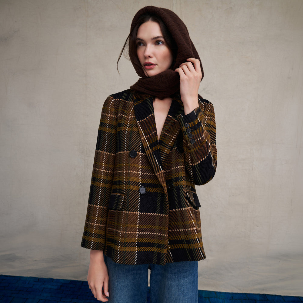 Woman wearing the O'Hara Blazer in Heritage Plaid with wide leg jeans on a beige background with blue floor