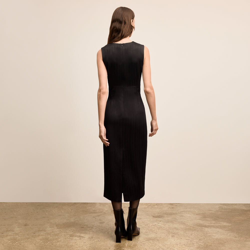 Woman wearing a black sleeveless dress against a beige background