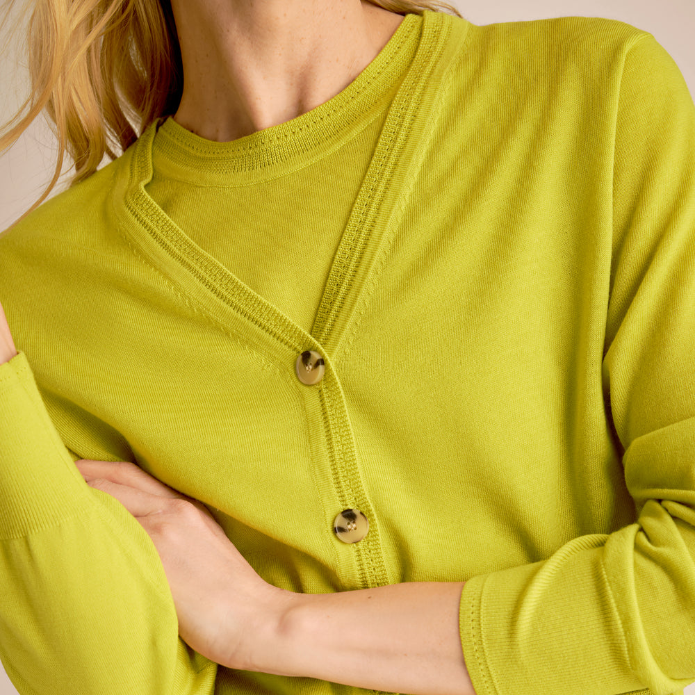Close-up of a person wearing a bright green cardigan with button details.