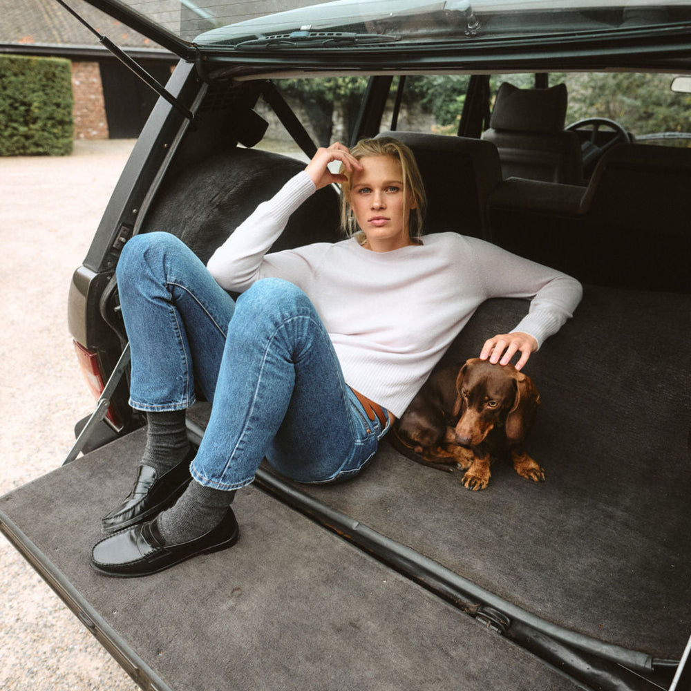 Woman sitting in the back of a car with a dog on a mat