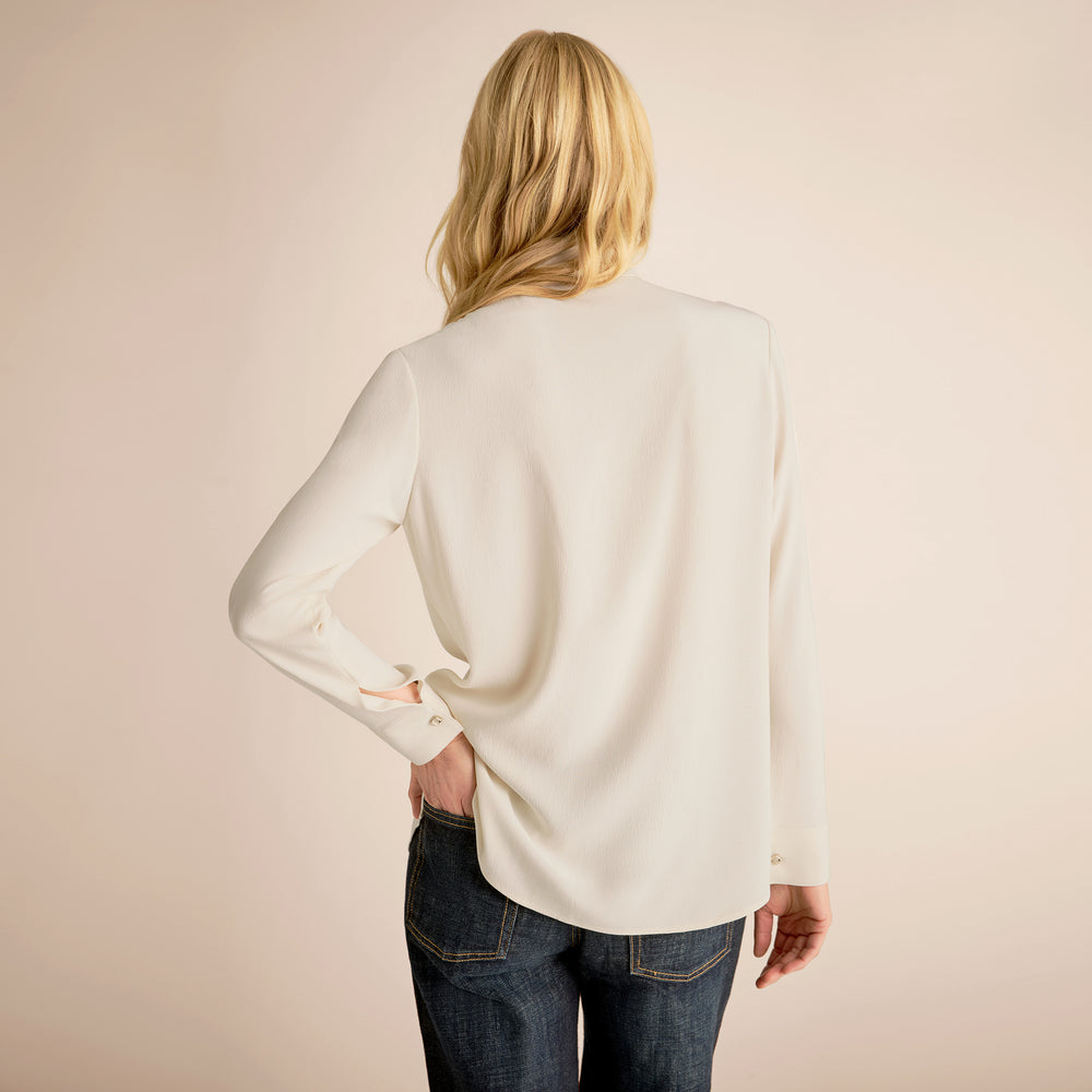 Person wearing a white sweater and blue jeans on a beige background