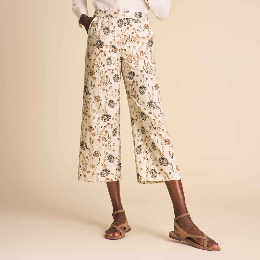 Person wearing floral pants on a beige background
