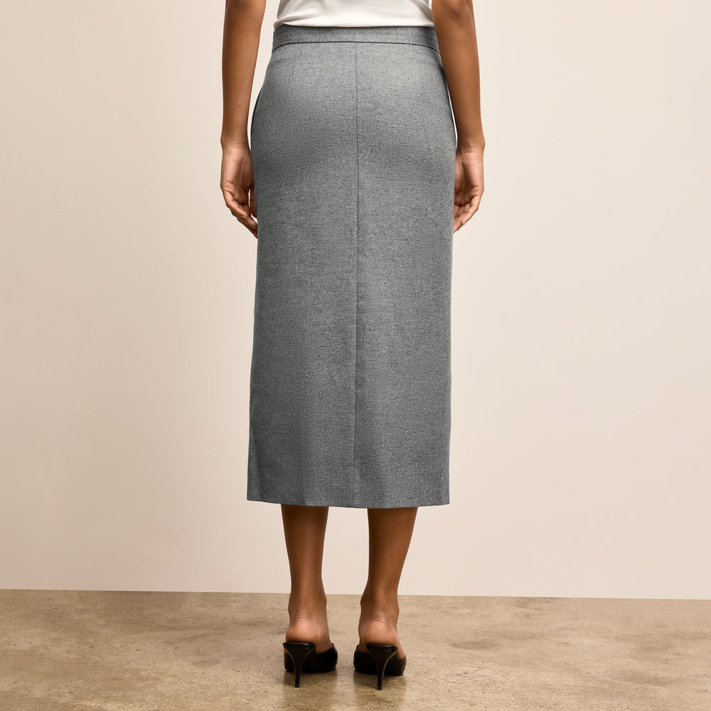 Person wearing a gray skirt on a plain background