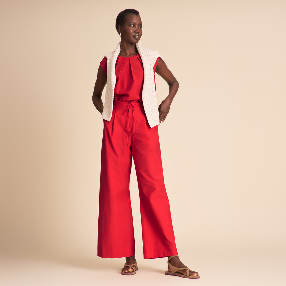 Woman wearing red pants on a beige background.