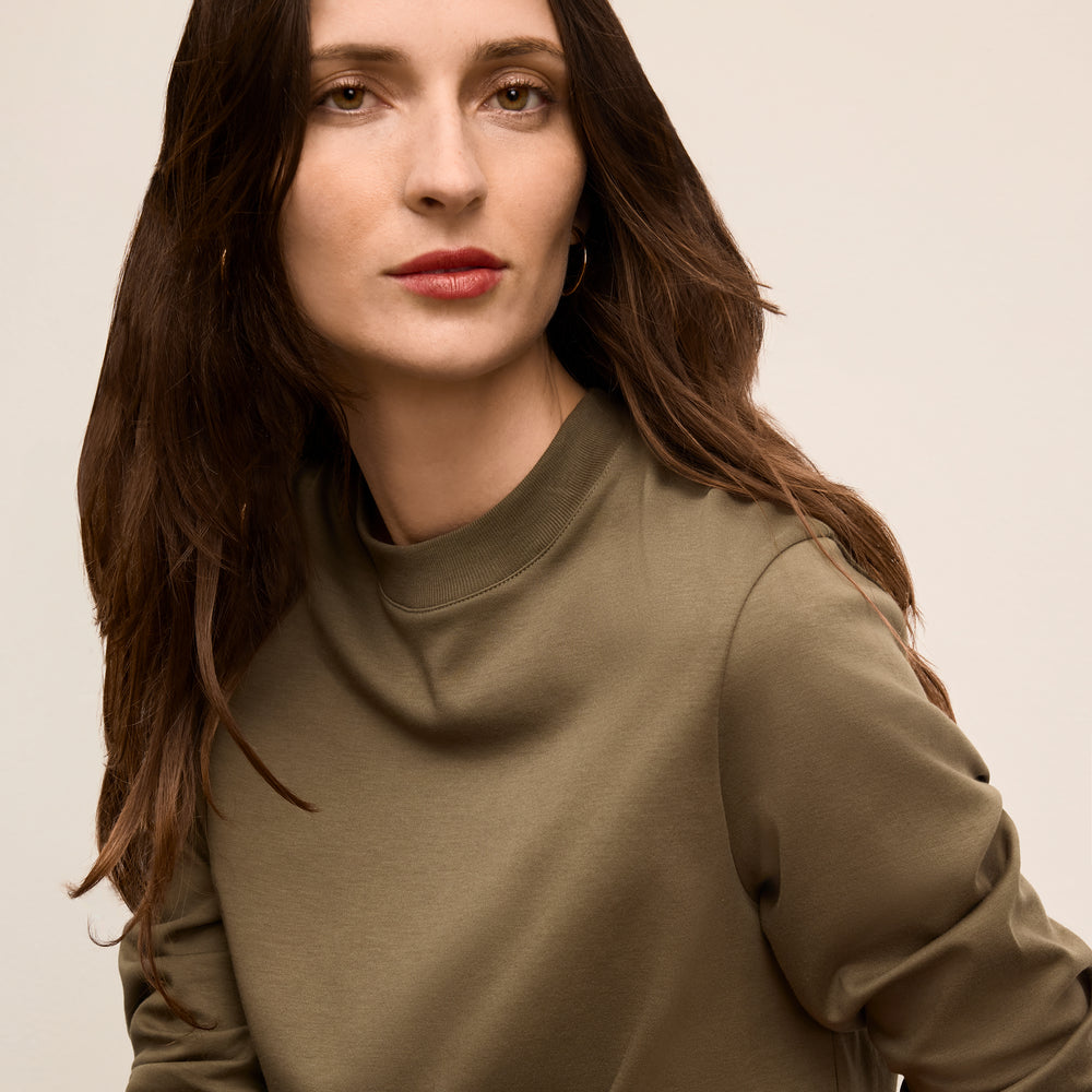 Woman wearing a green sweater against a beige background