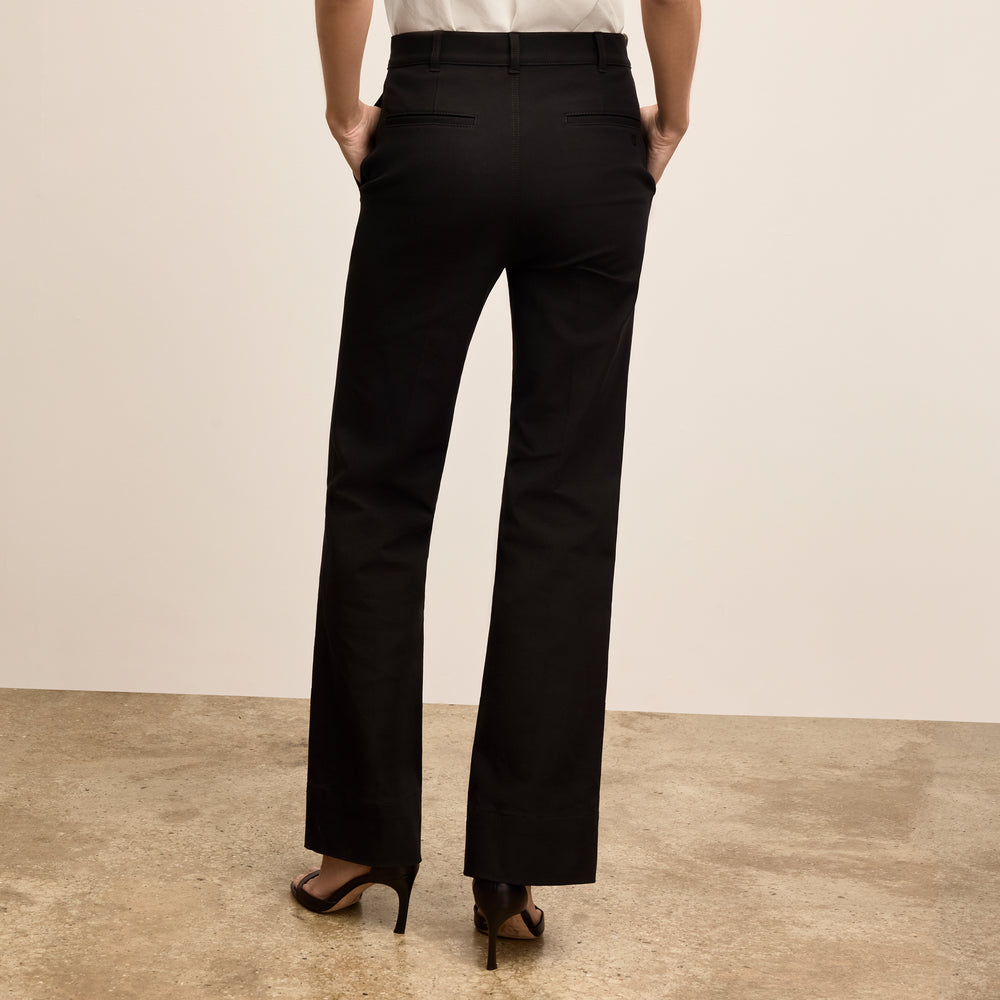 Person wearing black pants on a beige background