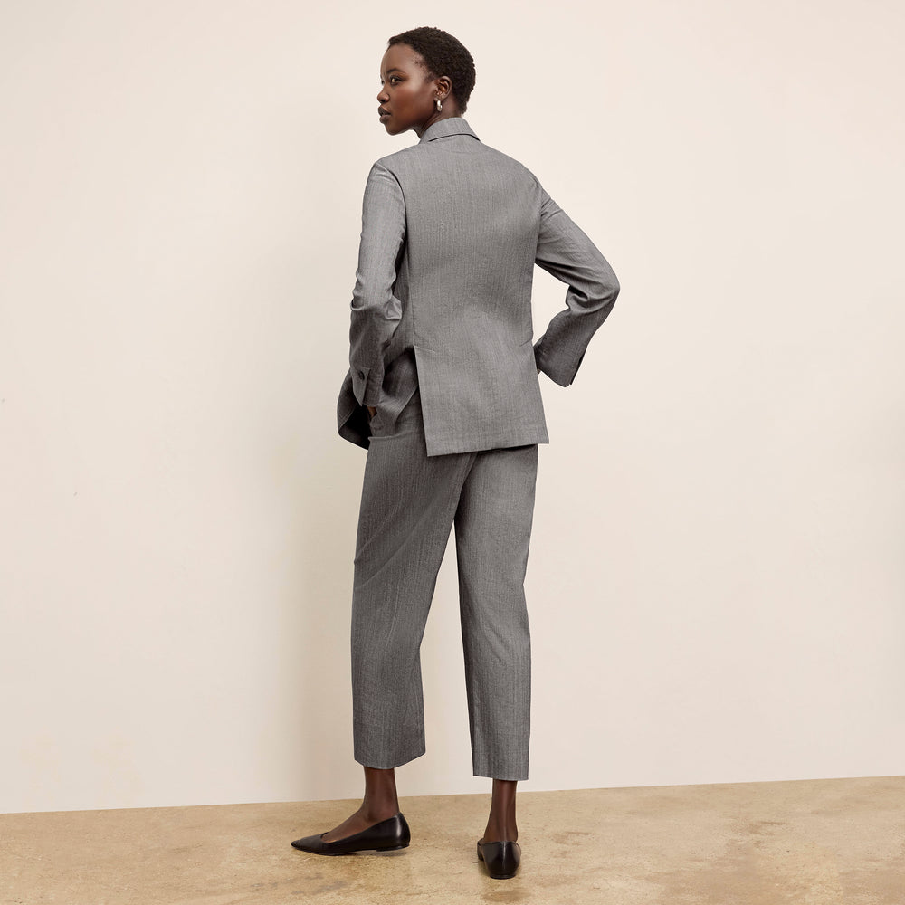 Person wearing a gray suit standing against a plain background