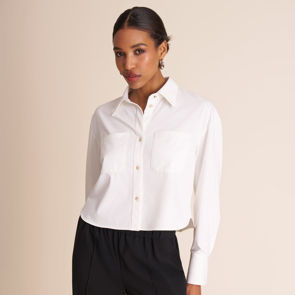 Woman wearing a white shirt and black pants against a beige background