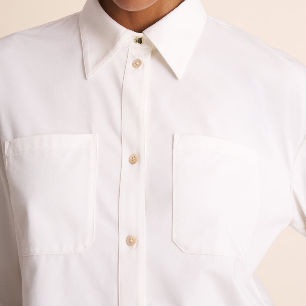 Close-up of a white button-up shirt with a beige background