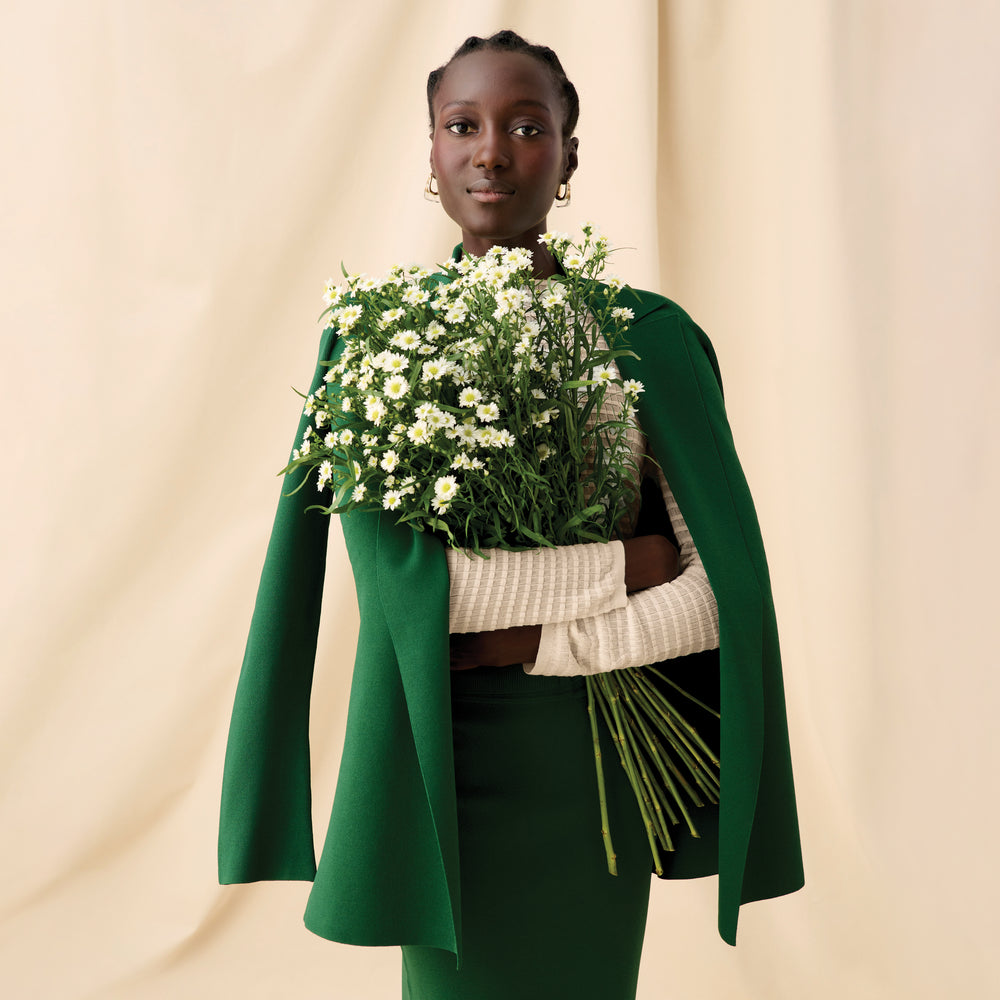 Front image of a woman holding flowers wearing the brodie top in meringue