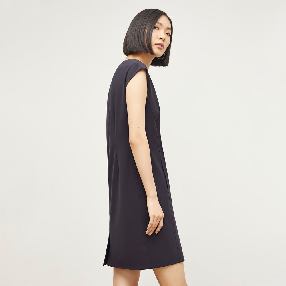 Back image of a woman standing wearing the Maaza Dress—Origami Suiting in Cool Charcoal