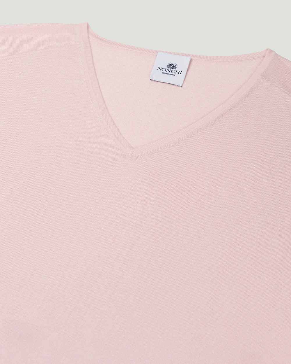 Close-up of a pink garment with a brand label on a light gray background