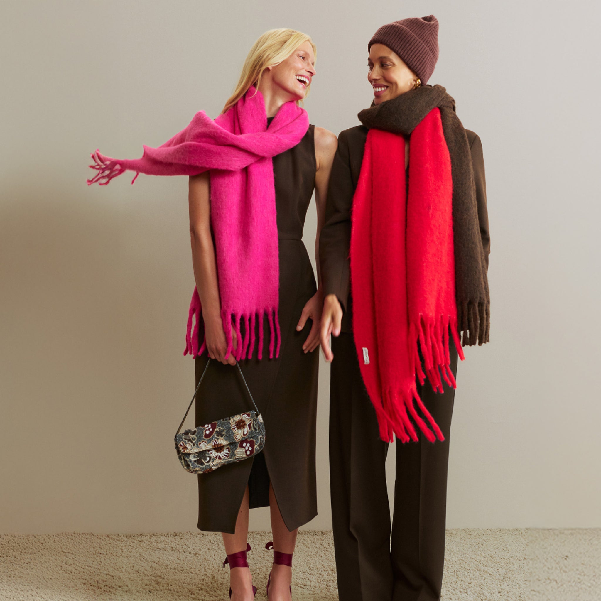 Two women wearing colorful scarves standing side by side against a neutral background