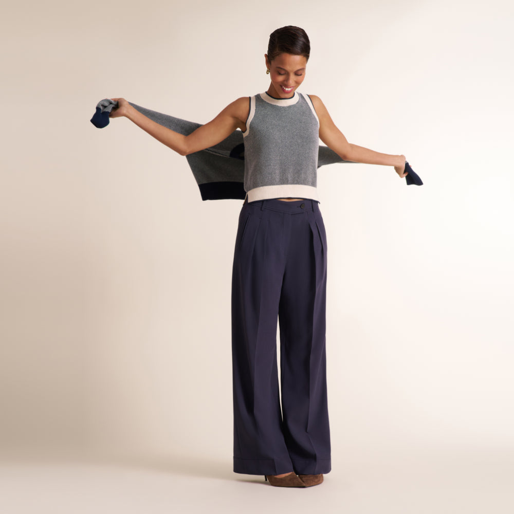 Woman wearing a navy and white knit tank top with navy pleated trouser pants