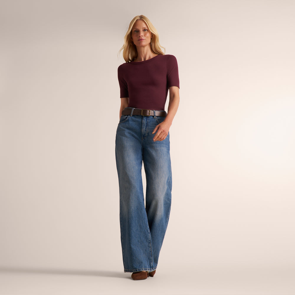 Woman wearing a short sleeve aubergine ribbed t-shirt with wide leg jeans