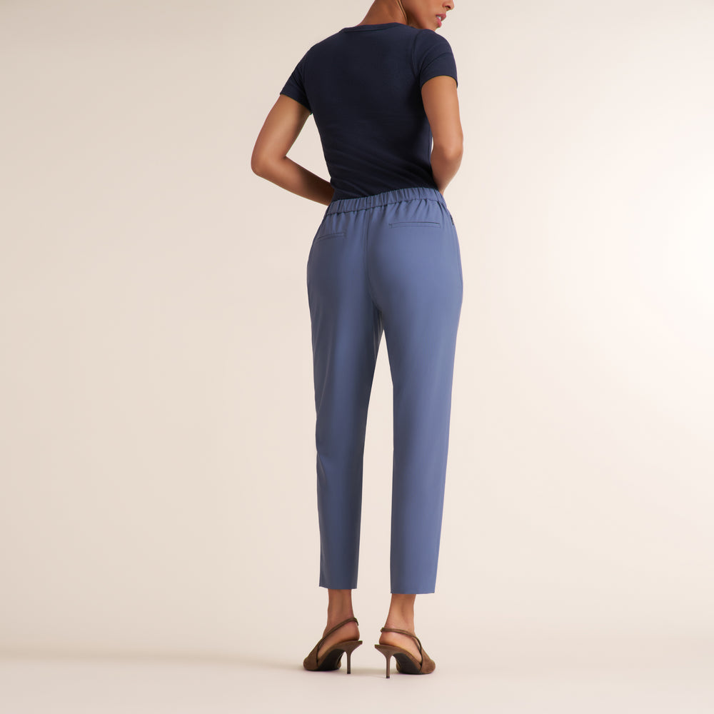 Woman wearing a scoop neck short sleeve navy t-shirt with light blue travel trousers