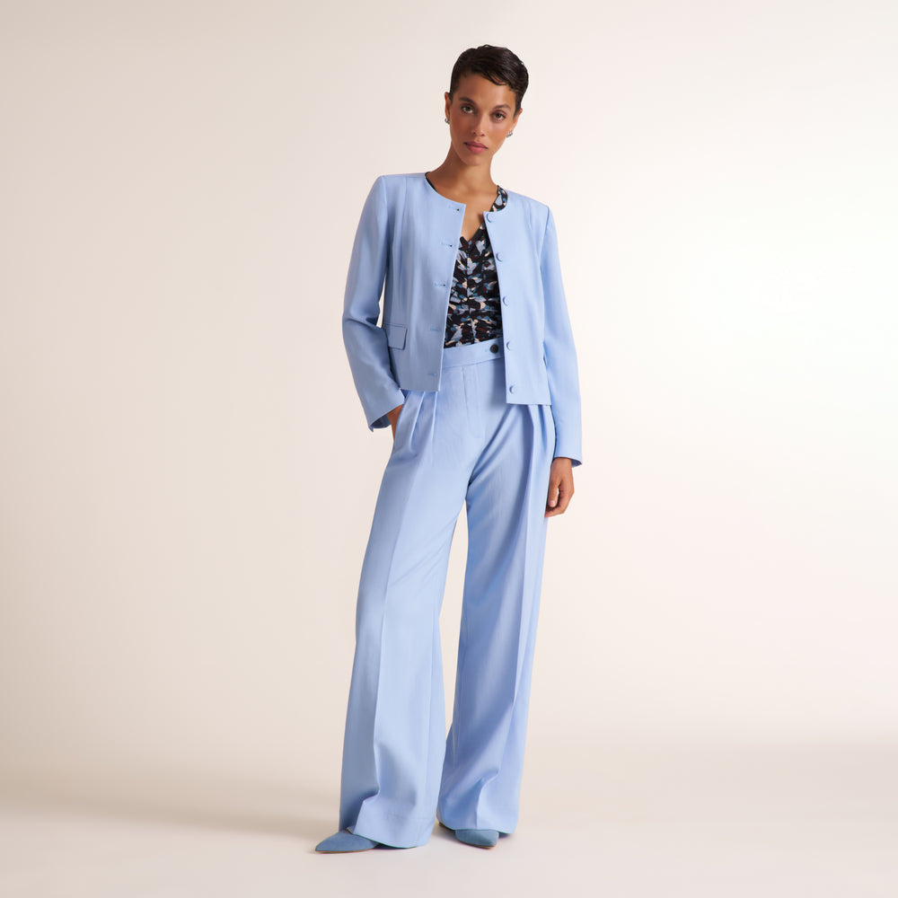 Woman wearing a light blue jacket and pant with a floral shirt
