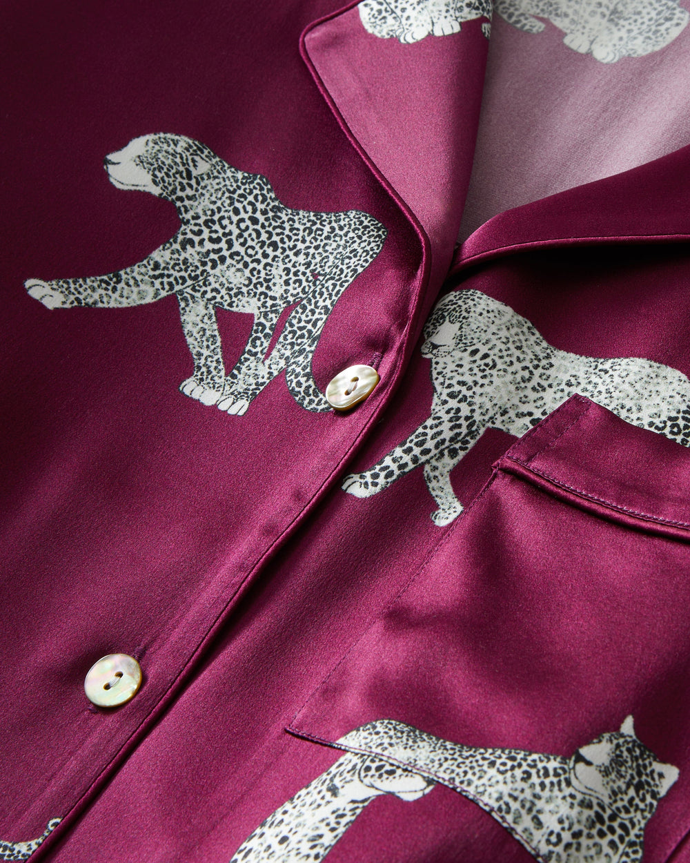 Close-up of a burgundy satin shirt with white leopard print details.