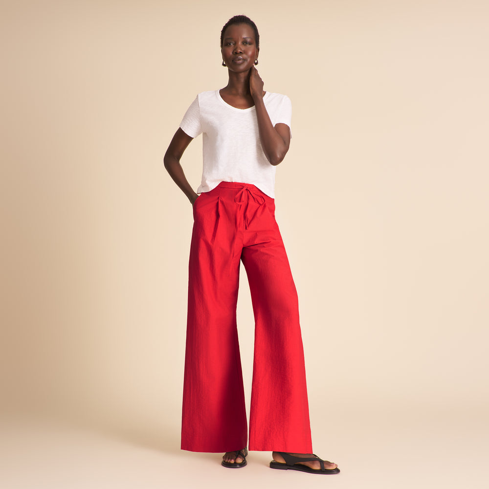 Woman wearing red pants on a beige background.