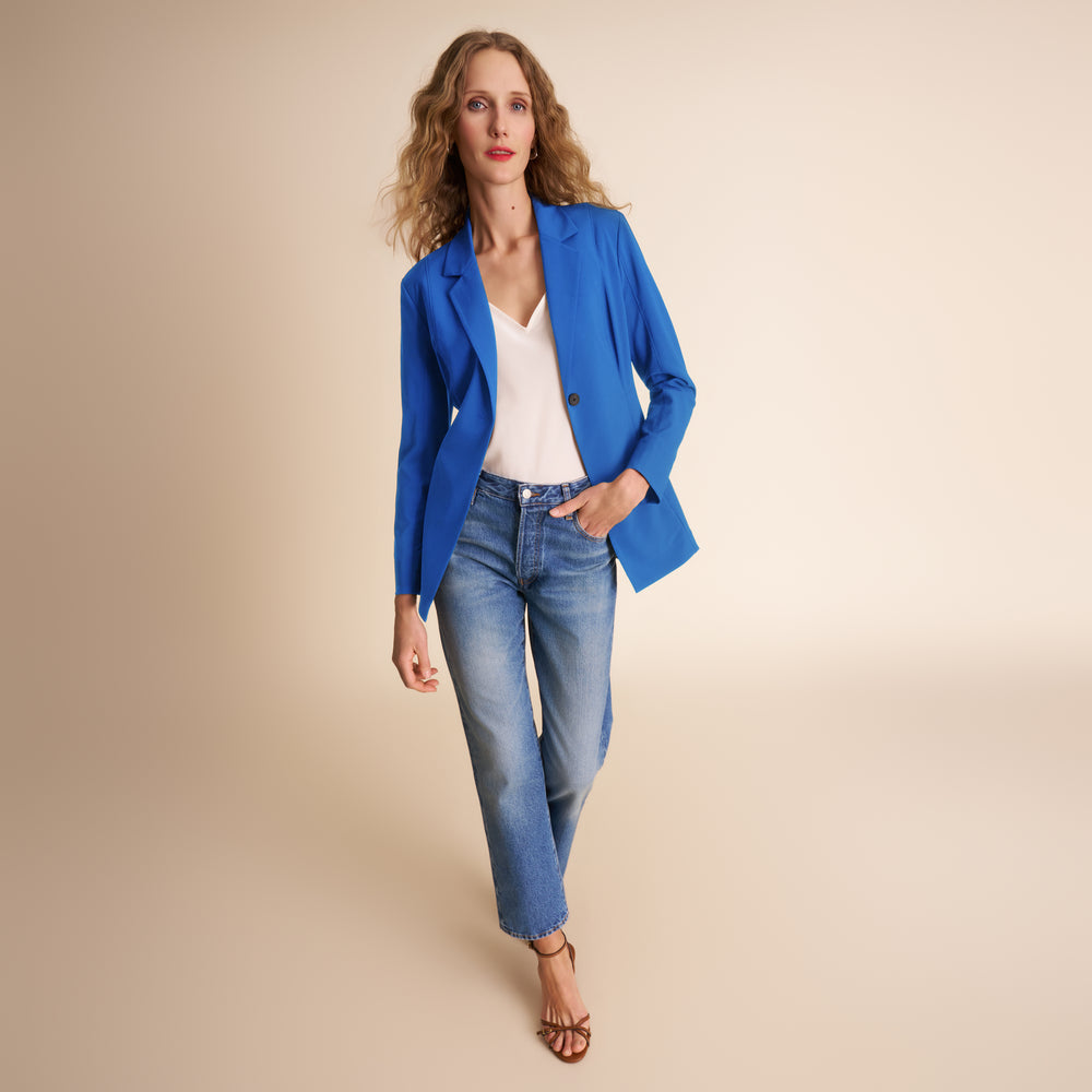 Woman wearing a blue blazer and jeans on a beige background