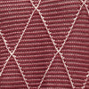 Close-up of a textured fabric with a geometric pattern in red and pink. 