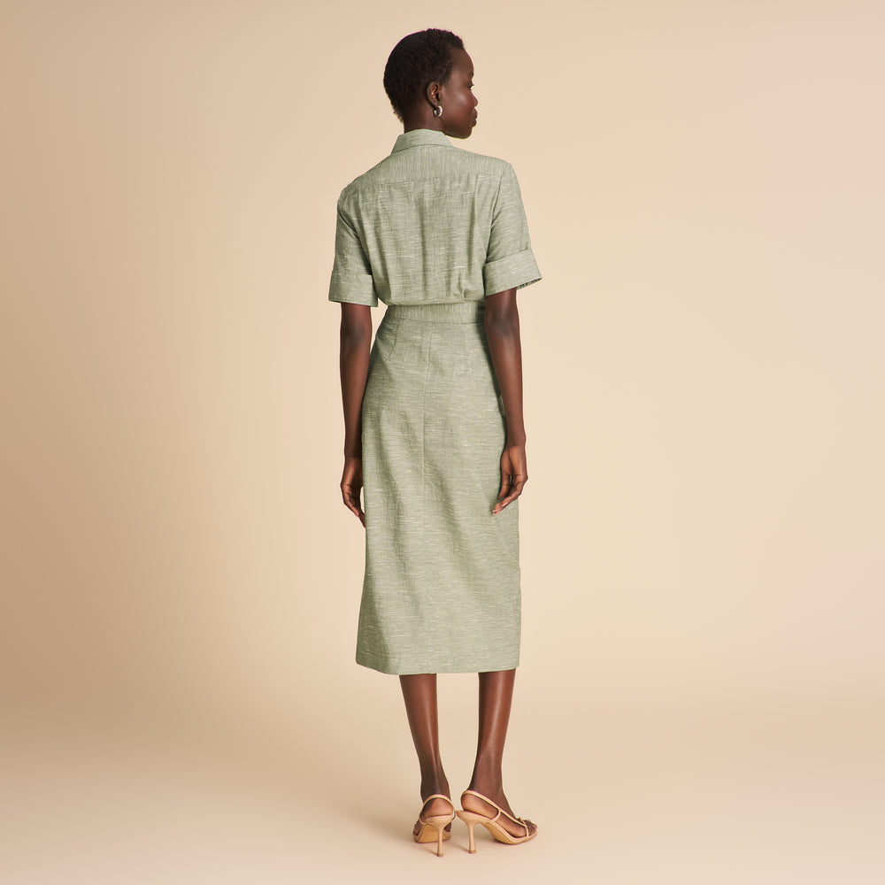 Woman wearing a green dress against a beige background
