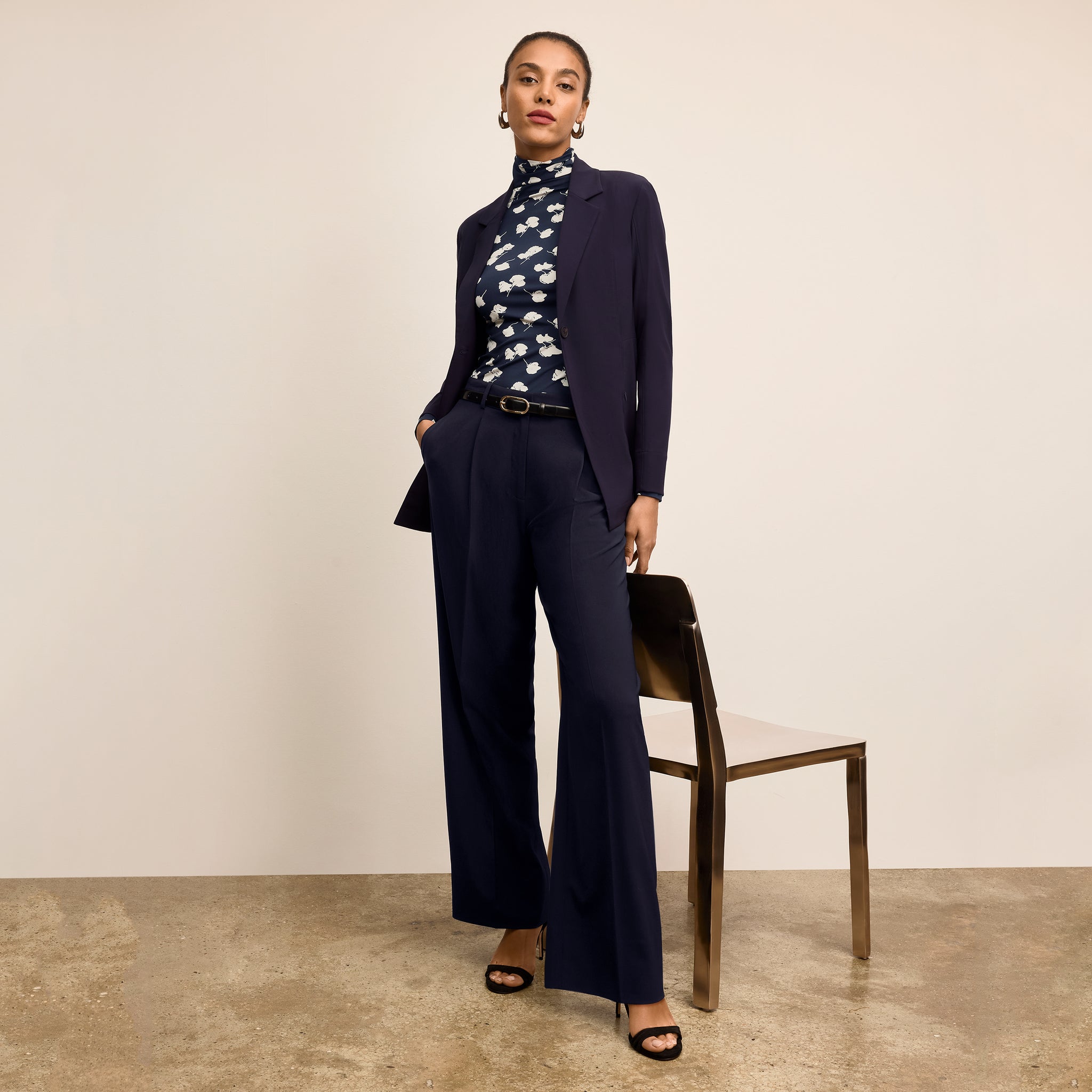 Woman wearing a navy suit with a floral blouse against a beige background